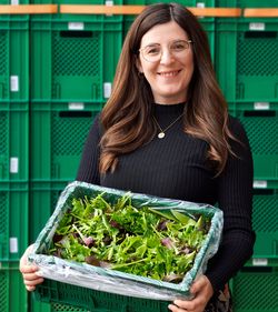 Frau mit einer Kiste frischem Salat in der Hand
