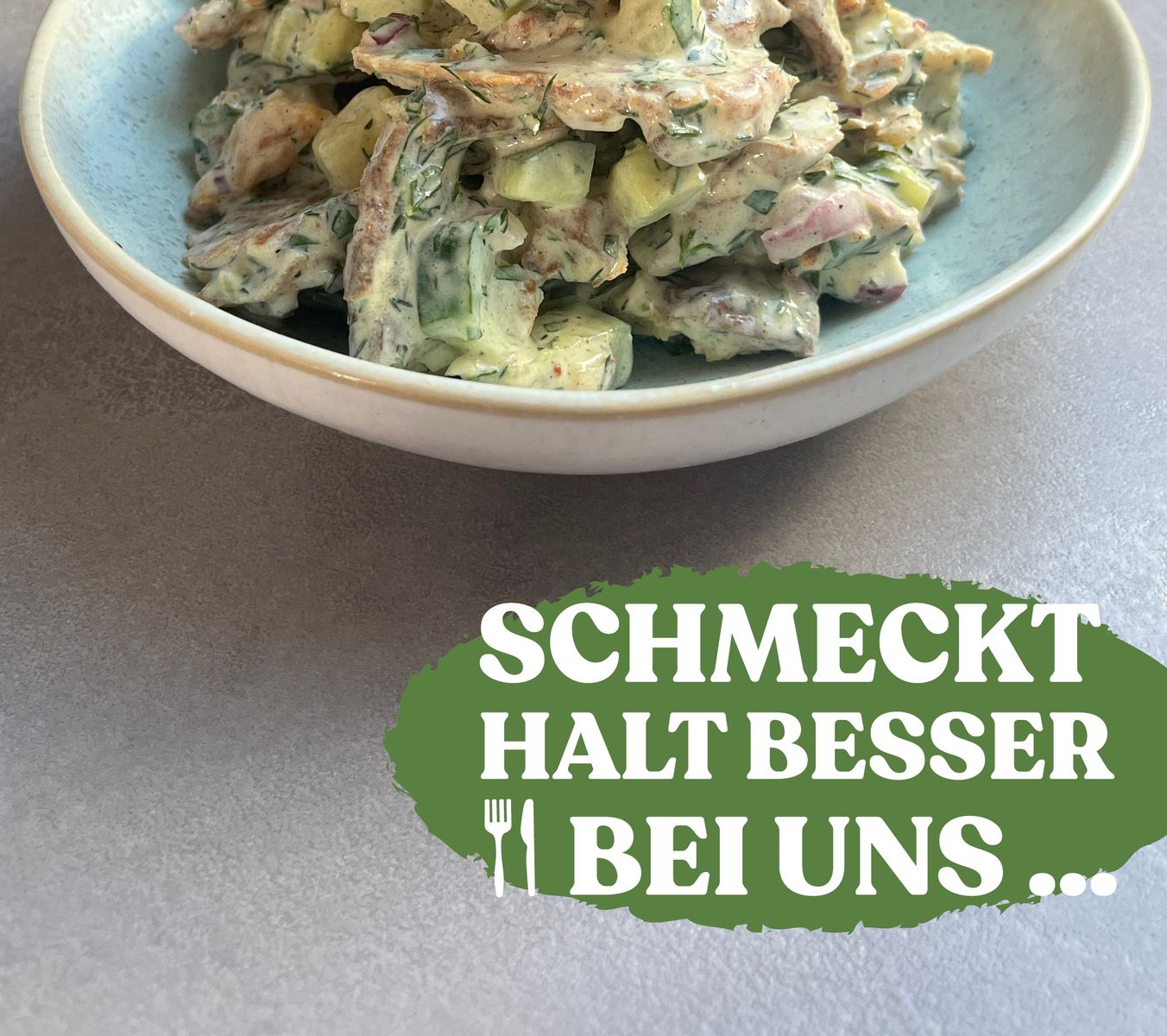 Eine Schüssel mit knusprigem Kartoffelsalat. Im Hintergrund die Zutaten